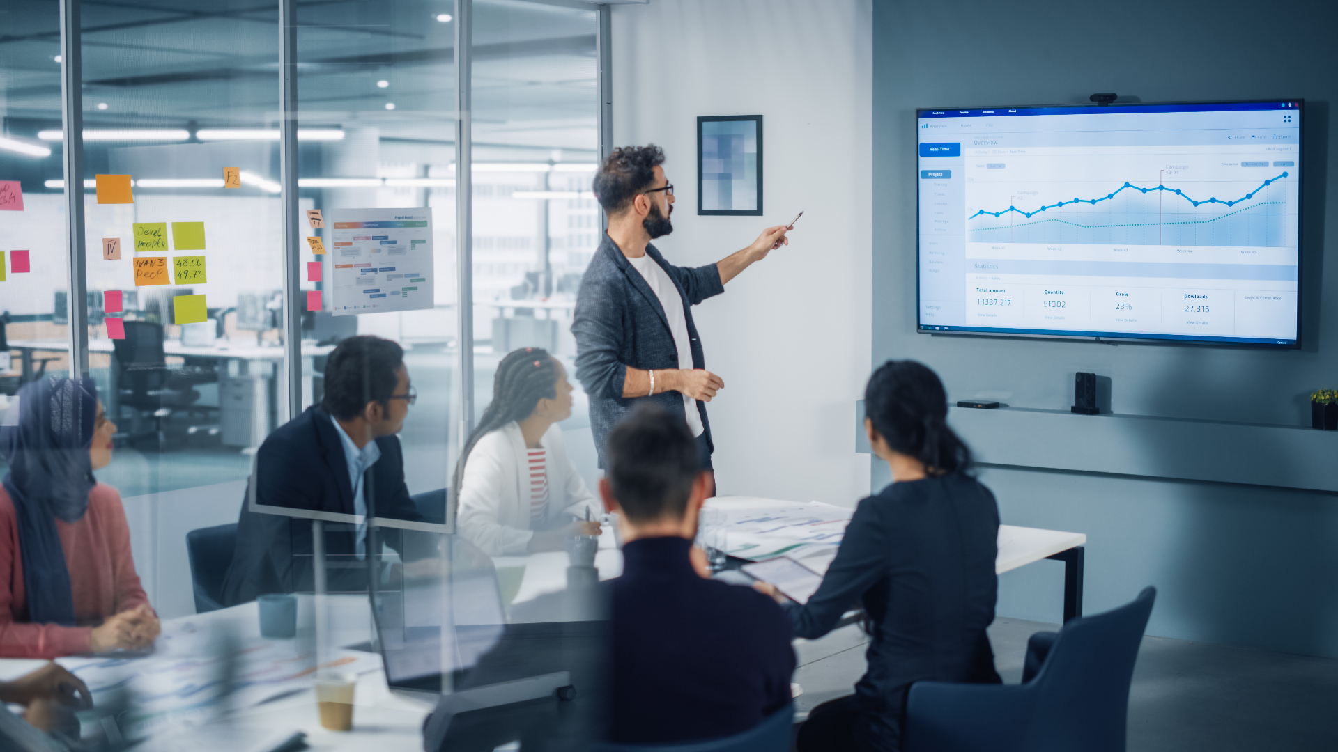 A team member presenting data analytics on a large screen during a meeting.
